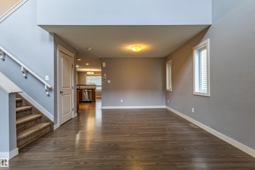 Open-concept living area featuring wood-finish flooring, a neutral color palette, and multiple windows - 17715 6 Avenue, Edmonton, AB - Indoor Photo Showing Other Room