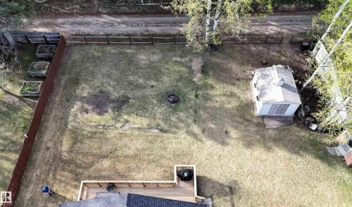 Expansive backyard featuring a wood deck, a storage shed, a fire pit area, and raised garden beds along the perimeter - 7126 4A Ave, Edson, AB - Outdoor With View
