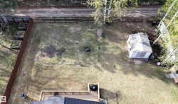 Expansive backyard featuring a wood deck, a storage shed, a fire pit area, and raised garden beds along the perimeter - 