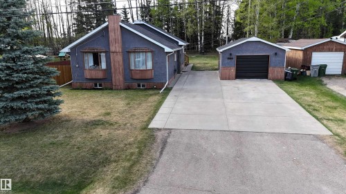 Exterior featuring gray siding, two prominent bay windows, and a detached single-car garage with a black door - 7126 4A Ave, Edson, AB - Outdoor