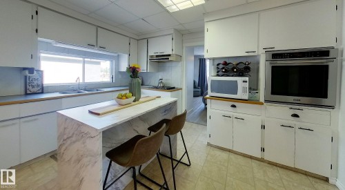 Kitchen featuring an integrated wall oven, white cabinetry, a dual basin sink, and a center island with seating - 7126 4A Ave, Edson, AB - Indoor Photo Showing Kitchen With Double Sink