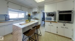 Kitchen featuring an integrated wall oven, white cabinetry, a dual basin sink, and a center island with seating - 