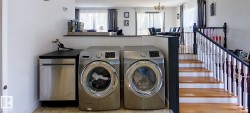 Integrated laundry area featuring stainless steel front-loading appliances and a built-in stainless steel dishwasher - 