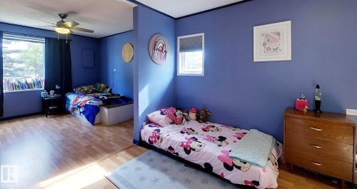 Spacious room featuring wood-finish flooring, multiple windows, and a ceiling fan with integrated lighting - 7126 4A Ave, Edson, AB - Indoor Photo Showing Bedroom