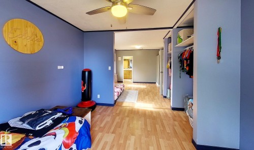 Interior space featuring wood-finish flooring, a ceiling fan with integrated lighting, and an open closet area with shelving - 7126 4A Ave, Edson, AB - Indoor
