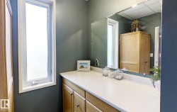 Vanity featuring a light countertop, natural wood-finish cabinetry, and an expansive mirror - 