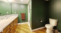 Spacious bathroom featuring a double vanity with wood cabinetry, a large integrated sink, and white subway tile backsplash - 
