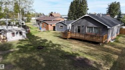 Rear exterior featuring a full-width wood deck, sliding glass door access, an additional shed, and a privacy fence - 