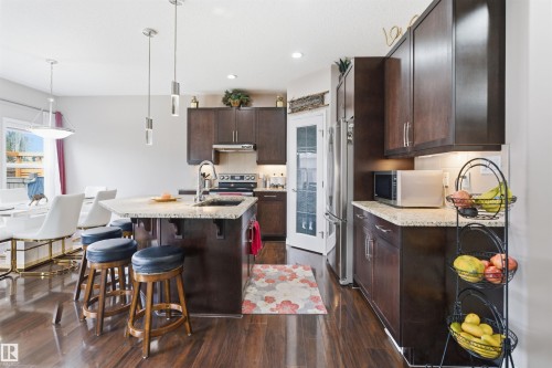 Kitchen featuring dark wood-finish cabinetry, light-toned countertops, and wood-finish flooring - 1444 37C Avenue, Edmonton, AB - Indoor Photo Showing Other Room