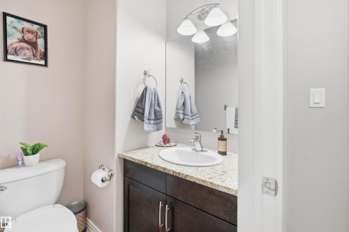 Bathroom featuring a dark wood-finish vanity, a speckled light-toned countertop, a white oval sink, and a four-light fixture - 1444 37C Avenue, Edmonton, AB - Indoor Photo Showing Bathroom
