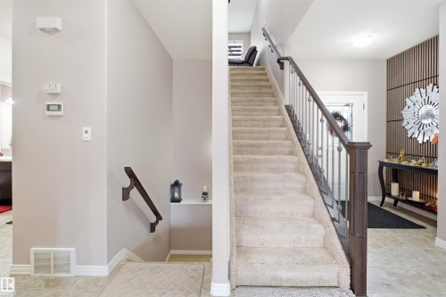 Carpeted staircase with dark wood newel post and metal balusters - 1444 37C Avenue, Edmonton, AB - Indoor Photo Showing Other Room