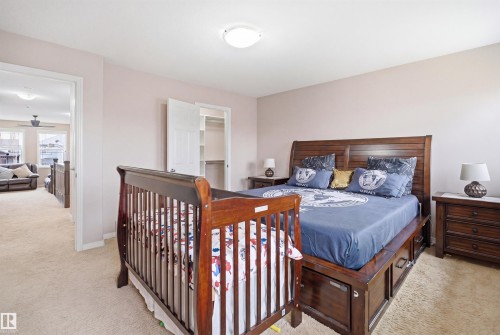 Carpeted bedroom featuring a flush mount ceiling light, light-colored walls, and a closet with a bifold door - 1444 37C Avenue, Edmonton, AB - Indoor Photo Showing Bedroom