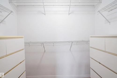 Walk-in closet featuring built-in wire shelving, multiple hanging rods, and two sets of white drawer units with wood-finish tops - 1444 37C Avenue, Edmonton, AB - Indoor With Storage