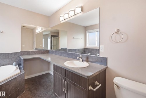 Bathroom featuring a built-in vanity with wood-finish cabinetry, a single basin sink, and an extended countertop - 1444 37C Avenue, Edmonton, AB - Indoor Photo Showing Bathroom