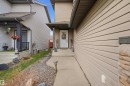 Exterior entry featuring a white paneled door, stone column accents, concrete walkway, and beige horizontal siding - 1444 37C Avenue, Edmonton, AB  - Outdoor With Exterior 