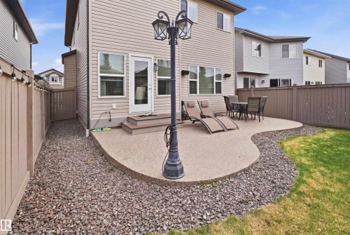 Rear exterior featuring a shaped concrete patio, a privacy fence, a gravel walkway, and a grassy lawn area - 1444 37C Avenue, Edmonton, AB - Outdoor