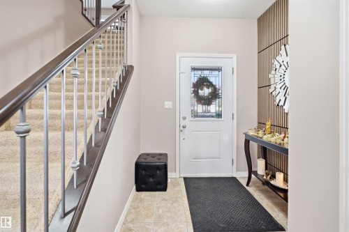 Entryway featuring tile flooring, a white front door with leaded glass insert, and a staircase with dark wood handrail and metal balusters - 1444 37C Avenue, Edmonton, AB - Indoor Photo Showing Other Room