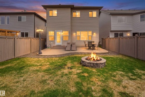 Fenced backyard featuring a stone fire pit, concrete patio, and exterior wall sconces - 1444 37C Avenue, Edmonton, AB - Outdoor With Deck Patio Veranda