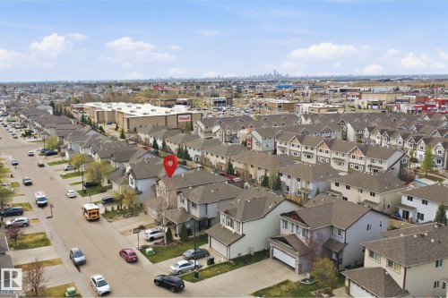 Aerial neighborhood perspective with a prominent commercial retail center, residential properties, and a distant city skyline - 1444 37C Avenue, Edmonton, AB - Outdoor With View