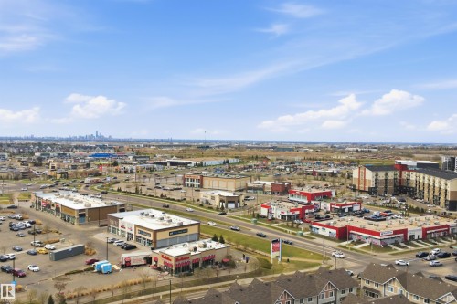 Aerial perspective showcasing a mixed-use commercial and residential district with distant city skyline - 1444 37C Avenue, Edmonton, AB - Outdoor With View