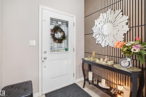 Entryway featuring a white door with a leaded glass insert, tiled flooring, and a decorative slatted accent wall - 1444 37C Avenue, Edmonton, AB - Indoor Photo Showing Other Room