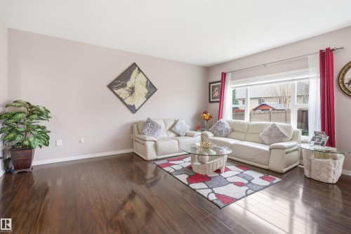 Spacious living area featuring polished wood-finish flooring, a large picture window, and neutral wall tones - 1444 37C Avenue, Edmonton, AB - Indoor Photo Showing Living Room