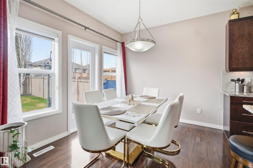 Dining area featuring wood-finish flooring, a contemporary pendant light fixture, and multiple windows with white trim - 1444 37C Avenue, Edmonton, AB - Indoor Photo Showing Dining Room