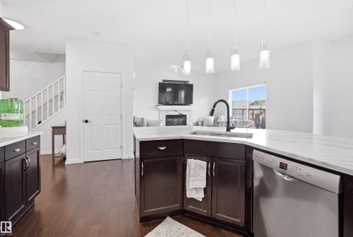 Kitchen featuring white countertops, dark wood-finish cabinetry, stainless steel dishwasher, and a gooseneck faucet - 1453 Hays Way, Edmonton, AB - Indoor Photo Showing Kitchen