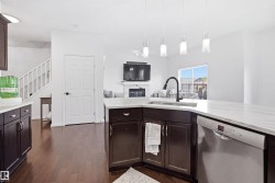 Kitchen featuring white countertops, dark wood-finish cabinetry, stainless steel dishwasher, and a gooseneck faucet - 