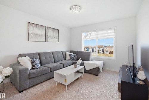 Carpeted living area featuring a large picture window, white walls, and a contemporary ceiling light fixture - 1453 Hays Way, Edmonton, AB - Indoor Photo Showing Living Room