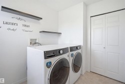 Dedicated laundry space featuring neutral-toned flooring and white walls - 