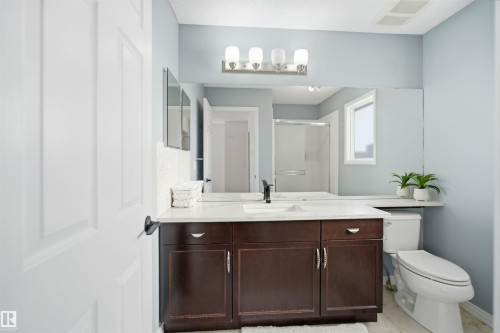 Bathroom featuring a dark wood-finish vanity with a white countertop and undermount sink, a large wall-mounted mirror, and a white toilet - 1453 Hays Way, Edmonton, AB - Indoor Photo Showing Bathroom