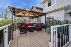 Expansive outdoor deck featuring wood-finish flooring, a pergola with a translucent canopy, white and black railings, and direct access to the interior via a sliding glass door - 
