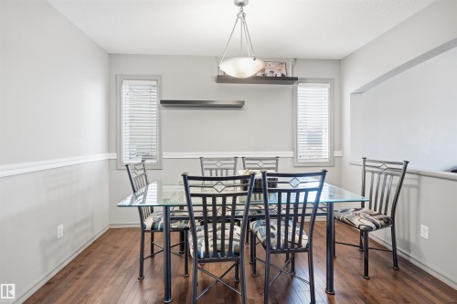 Recessed dining area featuring dark wood-finish flooring, a contemporary chandelier, two windows with blinds, and white chair rail molding - 1144 35 Avenue, Edmonton, AB - Indoor Photo Showing Dining Room
