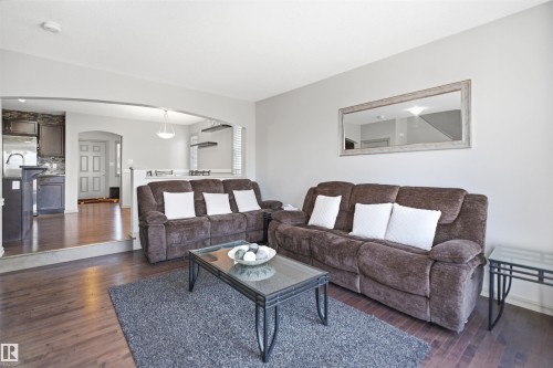 Spacious living area featuring wood-finish flooring, light gray wall paint, and an arched entryway - 1144 35 Avenue, Edmonton, AB - Indoor Photo Showing Living Room