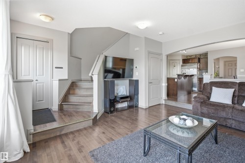 Entryway and living area featuring wood-finish flooring, a two-panel bi-fold closet, and a staircase with white risers - 1144 35 Avenue, Edmonton, AB - Indoor Photo Showing Living Room