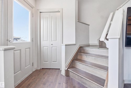 Entryway with wood-finish flooring, white panel door with upper window, bifold closet doors, and staircase with painted risers and wood-finish treads - 1144 35 Avenue, Edmonton, AB - Indoor Photo Showing Other Room