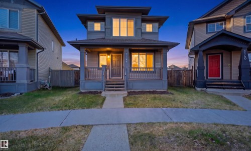 Modern residential exterior featuring a covered front porch, dark siding, multiple windows, and a concrete walkway - 1144 35 Avenue, Edmonton, AB - Outdoor With Deck Patio Veranda With Facade