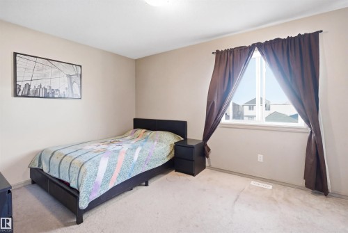 Carpeted room featuring neutral wall paint, a window with white trim, and a ceiling-mounted light fixture - 1144 35 Avenue, Edmonton, AB - Indoor Photo Showing Bedroom