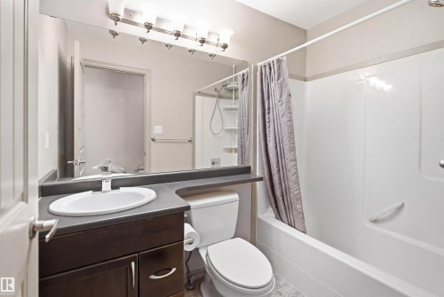 Full bathroom featuring a dark wood-finish vanity with a white oval sink, a large mirror, a four-light fixture, and a white shower/tub combination - 1144 35 Avenue, Edmonton, AB - Indoor Photo Showing Bathroom