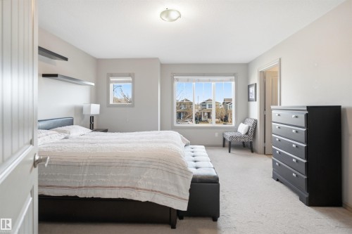 Light-filled sleeping area featuring neutral wall tones, plush carpeting, multiple windows, and floating wall shelves - 1144 35 Avenue, Edmonton, AB - Indoor Photo Showing Bedroom