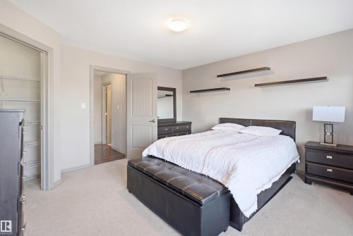 Carpeted bedroom featuring neutral wall tones, a ceiling-mounted light fixture, and a built-in closet with wire shelving - 1144 35 Avenue, Edmonton, AB - Indoor Photo Showing Bedroom