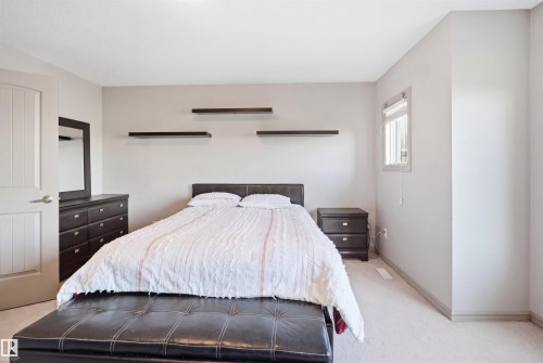 Spacious room featuring light-toned carpeting, a window with trim, neutral wall color, and a white paneled interior door - 1144 35 Avenue, Edmonton, AB - Indoor Photo Showing Bedroom