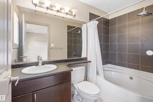 Bathroom featuring a dark wood-finish vanity with a single basin sink, a large mirror, and a five-light fixture - 1144 35 Avenue, Edmonton, AB - Indoor Photo Showing Bathroom