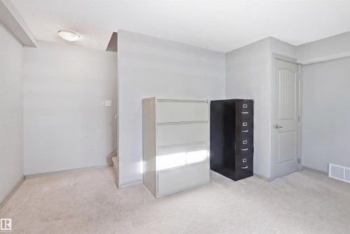Carpeted room featuring light gray walls, a flush-mount ceiling light, a white paneled door, and white baseboards - 1144 35 Avenue, Edmonton, AB - Indoor