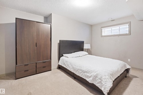 Recessed window with blinds, light beige carpeting, light gray wall paint, and white textured ceiling - 1144 35 Avenue, Edmonton, AB - Indoor Photo Showing Bedroom