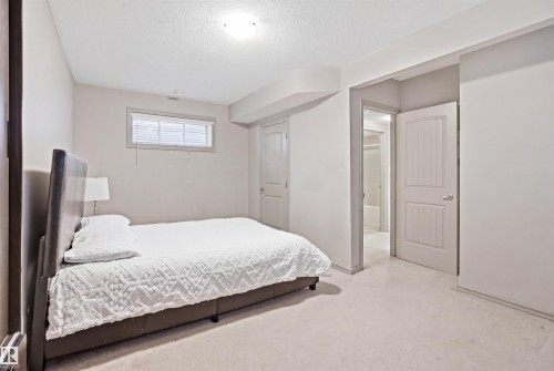 Carpeted bedroom featuring white walls, a single window with blinds, a white paneled door, and an overhead light fixture - 1144 35 Avenue, Edmonton, AB - Indoor Photo Showing Bedroom