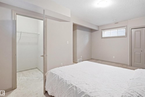 Carpeted room featuring a wire rack closet system, a horizontal window with blinds, and a paneled bifold door - 1144 35 Avenue, Edmonton, AB - Indoor Photo Showing Bedroom