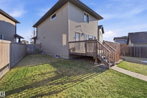 Rear exterior featuring a wood-decked patio with stairs, a fenced backyard with lawn space, and tan siding - 1144 35 Avenue, Edmonton, AB - Outdoor With Deck Patio Veranda With Exterior