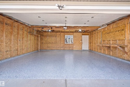 Spacious garage featuring a durable flake epoxy floor, exposed wood-frame walls, a white entry door, and a horizontal window providing natural light - 1144 35 Avenue, Edmonton, AB - Indoor Photo Showing Garage